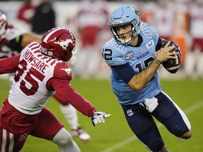 Toronto Argonauts quarterback Chad Kelly (12) protects the ball from Calgary Stampeders defensive lineman Julian Howsare (95) during first half CFL football action in Toronto on Friday, August 25, 2023.