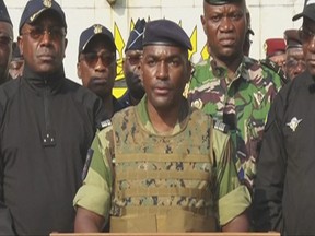 This video grab taken from a video obtained by AFPTV from Gabon 24 on Aug. 30, 2023 shows Colonel Ulrich Manfoumbi Manfoumbi (centre), spokesperson of the Committee for the Transition and Restoration of Institutions (CTRI), reading a statement on television.