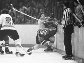 FILE -Philadelphia Flyers center Bobby Clarke (16) pushes Montreal Canadiens defenseman Bob Murdoch (23) into the boards in the third period of an NHL semifinal playoff game, April 22, 1973 in Philadelphia. Bob Murdoch, a two-time Stanley Cup champion and a former NHL defenseman, died at the age of 76, the NHL Alumni Association announced on Friday, Aug. 4, 2023.