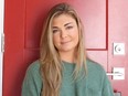 Pretty blonde woman standing against red door.