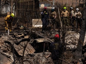 Search and recovery team members check charred buildings and cars in the aftermath of the Maui wildfires in Lahaina, Hawaii, on Aug. 18, 2023.