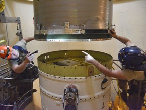 Missile maintenance technicians connect a re-entry system.