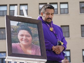 Carol Dubé, husband of Joyce Echaquan, stands next to a photo of his deceaced wife in front of the hospital where she died, in Joliette, Que., during a memorial on Sept. 28, 2021, marking the first anniversary of the death of his wife.