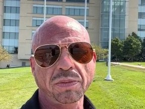Bald man with sunglasses in front of building