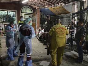 Forensic officers and a rescue worker arrive at a house where a woman and her two sons were killed and her husband was found severely injured, in Samut Prakan province on Aug. 28, 2023.