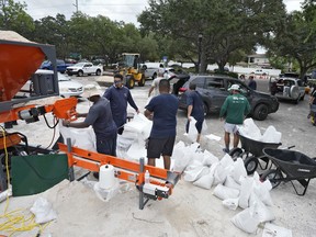 Members of the Tampa, Fla., parks and Recreation Dept., help residents with sandbags Monday, Aug. 28, 2023, in Tampa, Fla.