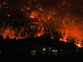 The McDougall Creek wildfire burns on the mountainside above houses in West Kelowna, B.C., Friday, August 18, 2023.