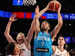 Mike Tobey of Slovenia drives to the basket against Niels Giffey and Johannes Voigtmann of Germany.