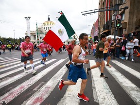 A runner competes with a Mexico flag during the 2023 Mexico City Marathon on August 27, 2023.