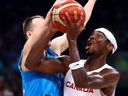 Shai Gilgeous-Alexander of Canada drives to the basket against Klemen Prepelic of Slovenia.
