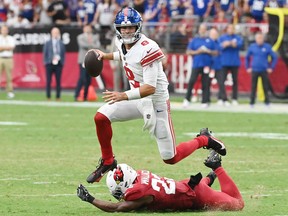 Daniel Jones of the New York Giants avoids a tackle from K'Von Wallace of the Arizona Cardinals.