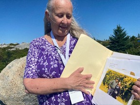 Claire Mortimer poses with a photo of herself and her father, John Mortimer, who died in the Swissair Flight 111 plane crash in Sept. 1998, at the Peggy's Cove Swissair Memorial in Indian Harbour, N.S. on Sunday, Sept.3, 2023.