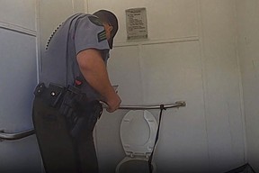 In this photo released by the Michigan State Police, a Department of Natural Resources sergeant talks with a woman who became trapped in an outhouse toilet after attempting to retrieve her Apple Watch, Tuesday, Sept. 19, 2023, at Dixon Lake in Bagley Township, Mich.