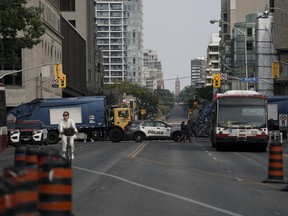 Toronto Police cars and city garbage trucks block the roads surrounding Queen’s Park in anticipation of a protest, in Toronto on Sept. 26, 2023. THE CANADIAN PRESS/Arlyn McAdorey