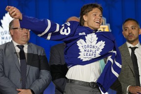 Easton Cowan puts on a Maple Leafs jersey after being picked by the team during the first round of the NHL hockey draft Wednesday, June 28, 2023, in Nashville, Tenn. THE ASSOCIATED PRESS FILES