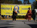 Women walk past a banner that includes a photograph of late temple president Hardeep Singh Nijjar outside the Guru Nanak Sikh Gurdwara Sahib in Surrey, B.C., on Monday, Sept. 18, 2023. Prime Minister Justin Trudeau says Canadian intelligence services are investigating 
