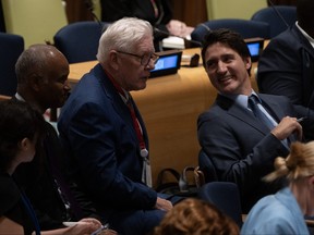 Prime Minister Justin Trudeau smiles as he speaks with Canada’s Ambassador to the United Nations Bob Rae and International Development Minister Ahmed Hussen.