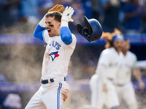 Cavan Biggio arms up and baseball helmet falling off behind him
