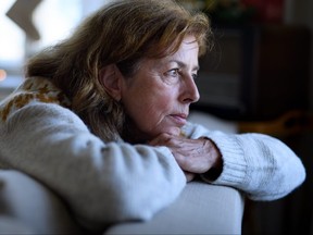 Lonely senior woman sitting on sofa indoors at Christmas, solitude