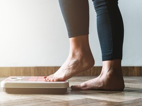 A woman weighing herself on a scale.