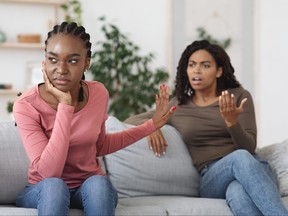 Annoyed woman showing stop gesture to her scolding sister