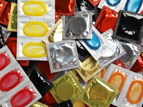 Pile of different condoms as background, top view
