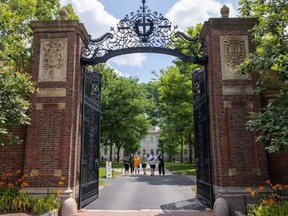 People walk through the gate on Harvard Yard at the Harvard University campus in Cambridge, Mass., June 29, 2023.