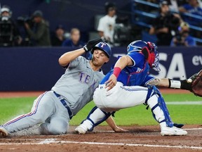 Texas Rangers' Corey Seager (left) scores ahead of the tag from Blue Jays catcher Tyler Heineman at Rogers Centre last night. The Jays lost 6-3. Nathan Dennette/The Canadian Press