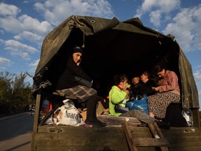 Refugees sit on the back of a truck with loaded belongings near Kornidzor on Sept. 28, 2023.