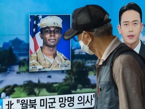 a man walks past a television showing a news broadcast featuring a photo of U.S. soldier Travis King
