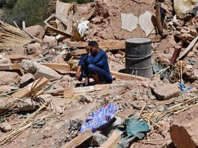A man cries as he sits on the rubble