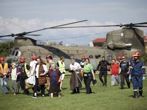 evacuees from flooded villages arrive by helicopter at a soccer stadium