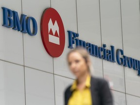 A person makes their way past the Bank of Montreal (BMO) building in the Financial District of Toronto, on Monday, Aug. 14, 2023.