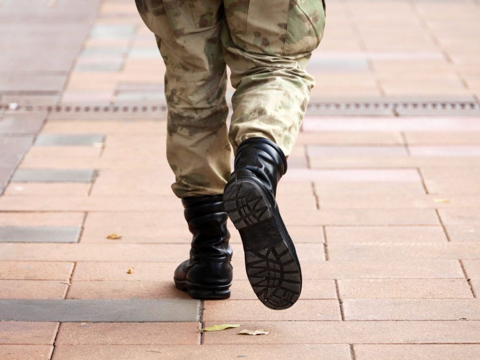 Men in camouflage trousers riding a pink tank and carrying rainbow