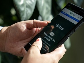 A person holds a phone displaying the home page of Metro Media