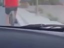 Screenshot of video taken by passenger of car driving up behind cyclist in red shirt.
