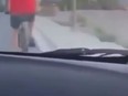 Screenshot of video taken by passenger of car driving up behind cyclist in red shirt.