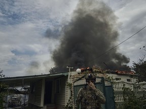 A Ukrainian soldier passes by a burning house