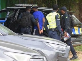 Suspected serial killer Ronaldo Ricketts, blue shirt, is taken into custody in Montego Bay. JAMAICA CONSTABULARY
