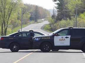 OPP vehicles block a road near the scene of a shooting where one Ontario Provincial Police officer was killed and two others were injured in the town of Bourget, Ont., on Thursday, May 11, 2023. Ontario's police watchdog has cleared an officer who fired his gun during a shooting in May that left another officer dead.