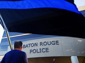 FILE - Brian Armoney of Baton Rouge holds a flag following a "Law Enforcement Support" ride in front of the Baton Rouge Police headquarters in Baton Rouge, La. Tuesday, July 19, 2016. The embattled Baton Rouge Police Department on Friday, Sept. 29, 2023, announced the arrest of three of its own officers, including a deputy chief, on charges they covered up a 2020 episode in which a suspect was struck and Tased during a strip-search in a department bathroom.