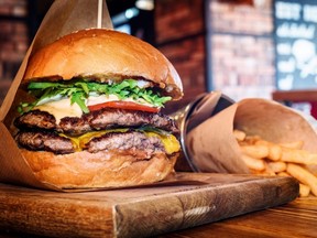 A burger and fries are seen on a wooden table at a restaurant.