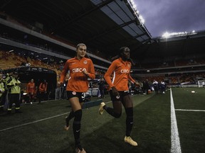 Sydney Collins (left) and Simi Awujo run on the field at Stade Marie-Marving in Le Mans, France on April 11, 2023, ahead of Canada's 2-1 loss to France in a soccer friendly.