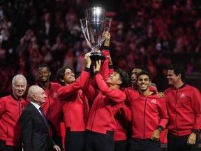 Team World's Taylor Fritz, centre left, and Ben Shelton, centre right, hoist the Laver Cup in front of their teammates, John McEnroe, back left, and Rod Laver, front left, after Team World defeated Team Europe 13-2 at the Laver Cup tennis tournament, in Vancouver, on Sunday, September 24, 2023.&ampnbsp;Team World claimed its second straight Laver Cup title on Sunday at Rogers Arena.&ampnbsp;THE CANADIAN PRESS/Darryl Dyck
