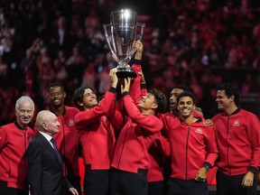 Team World's Taylor Fritz, centre left, and Ben Shelton, centre right, hoist the Laver Cup in front of their teammates, John McEnroe, back left, and Rod Laver, front left, after Team World defeated Team Europe 13-2 at the Laver Cup tennis tournament, in Vancouver, on Sunday, September 24, 2023. Team World claimed its second straight Laver Cup title on Sunday at Rogers Arena. THE CANADIAN PRESS/Darryl Dyck