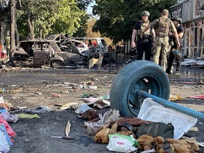 Ukrainian police and rescuers stand near wreckage following a Russian strike