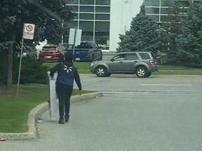 Man in Walmart vest walking from store with TV.