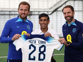 Britain's Prime Minister Rishi Sunak (C) poses with England striker Harry Kane (L) and manager Gareth Southgate during a visit to St George's Park.