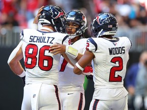 Dalton Schultz, C.J. Stroud and Robert Woods of the Houston Texans celebrate after scoring a touchdown.