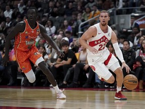 Toronto Raptors point guard Malachi Flynn (22) dribbles the ball as he runs while being followed by Cairns Taipans forward Bul Kuol.